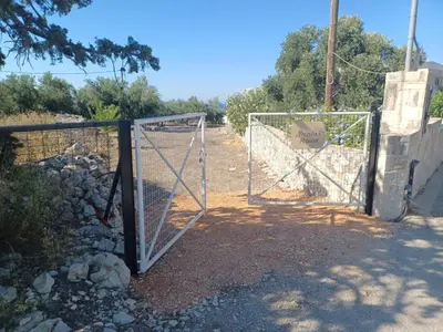 a gate with a sign on it on a dirt road at Nicola's House in Tsivarás
