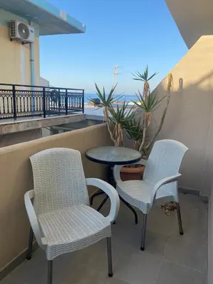 two chairs and a table on a balcony with the ocean at Tile Apartments 4 in Agia Marina Nea Kydonias