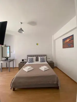 a bedroom with a large bed and a flat screen tv at Tile Apartments 6 in Agia Marina Nea Kydonias