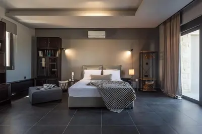 a bedroom with a bed and a ottoman in it at Calmar Boutique Villa 5min drive to Kolymvari beach with Private Pool & Sea Views in Kolymvari