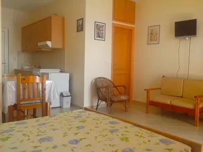 a living room with a couch a chair and a kitchen at Seaview Studio in beautiful setting, west from Chania in Ravdhoúkha