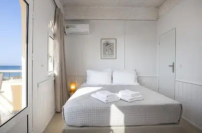 a white bedroom with a bed with towels on it at Neachora Beachfront Suites in Chania Town