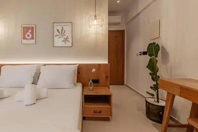 a bedroom with a white bed and a potted plant at Sarana Suites Crete in Kissamos