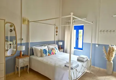 a bedroom with a white canopy bed and a mirror at Sfakia On the Beach in Khóra Sfakíon