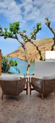 a patio with two chairs and a table and a lake at Sfakia On the Beach in Khóra Sfakíon