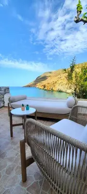 a patio with two chairs and a table and a boat at Sfakia On the Beach in Khóra Sfakíon