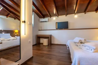 a bedroom with two beds and a tv on the wall at Pallazzo Dei Miracoli - Luxe 3BR apt Sea & Old Port Terrace View in Chania Town
