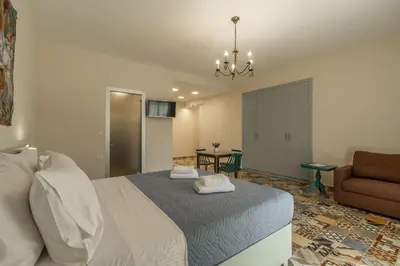 a bedroom with a bed and a couch and a chair at Altirina Studios in Almirida