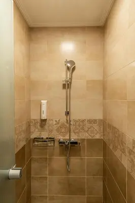 a shower in a bathroom with aige tiled wall at Altirina Studios in Almirida