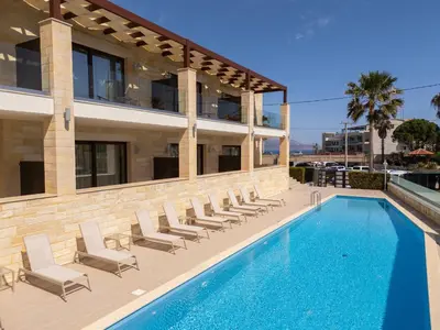 a swimming pool with chairs and a building at Altirina Studios in Almirida