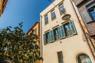 a building with green shutters and a clock on it at Panaretos Deluxe Maisonette in Chania Town