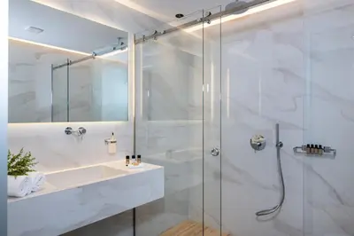 a white bathroom with a shower and a sink at EdgeWater Beach Hotel in Chania Town