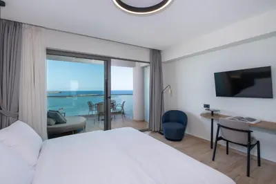 a bedroom with a bed and a view of the ocean at EdgeWater Beach Hotel in Chania Town