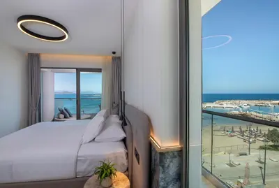 a bedroom with a bed and a view of the ocean at EdgeWater Beach Hotel in Chania Town