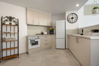 a kitchen with white appliances and a clock on the wall at Cozy Light Nest Chania Crete in Kounoupidhianá