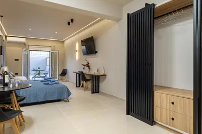 a hotel room with a bed and a dining room at Dom Azure Studios in Agia Marina Nea Kydonias