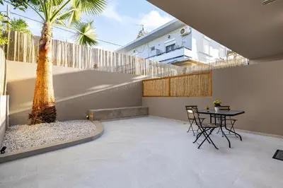 a patio with a table and a palm tree at Dom Azure Studios in Agia Marina Nea Kydonias