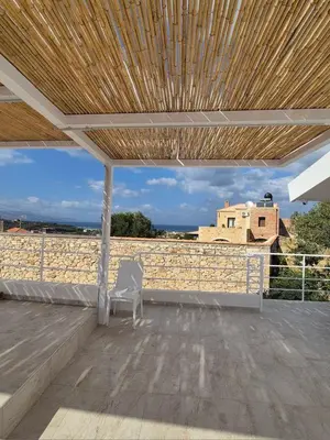 a white chair sitting on a patio with a wooden roof at Aldea Apartments in Módhion