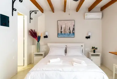 a white bedroom with a white bed with two white towels at Amy's Little Gem in Chania Town