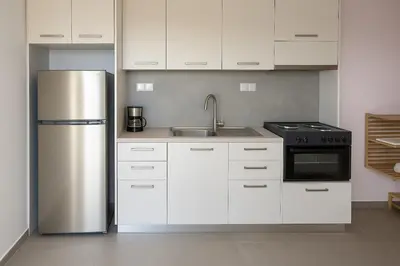 a kitchen with white cabinets and a stainless steel refrigerator at Yalos Standard Studio - 5 mins to Elafonisi beach in Agios Padeleimon