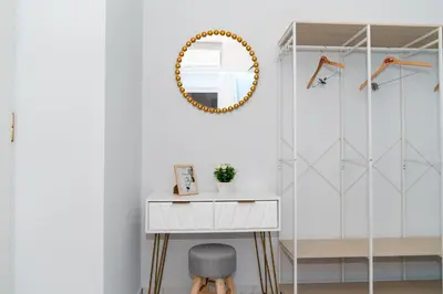 a white bathroom with a mirror and a table at Nafsika's Cozy Apartment in Chania Town