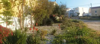 a garden with flowers and plants next to a building at ARETOUSA Seafront House in Kalyves