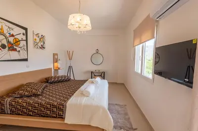 a bedroom with a bed and a television and a window at ARETOUSA Seafront House in Kalyves