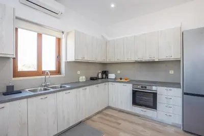 a kitchen with white cabinets and a sink and a window at Villa Andromeda Fres in Frés