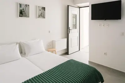 a white bedroom with a bed and a flat screen tv at Yalos Tiny Studio - 5 mins to Elafonisi beach in Agios Padeleimon
