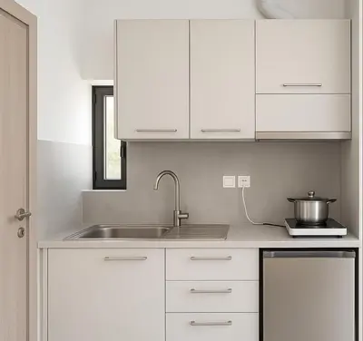a kitchen with white cabinets and a sink at Yalos Tiny Studio - 5 mins to Elafonisi beach in Agios Padeleimon