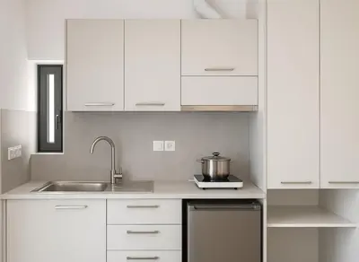 a kitchen with white cabinets and a sink at Yalos Tiny Studio - 5 mins to Elafonisi beach in Agios Padeleimon
