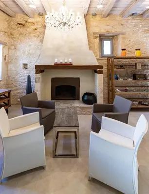 a living room with a fireplace and chairs at Villa Athermigo in Gavalochori