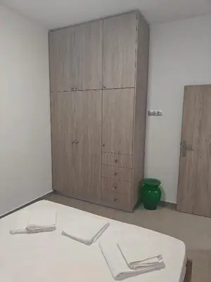 a room with a bed and a wooden cabinet at Chrissos apartment in Agios Padeleimon