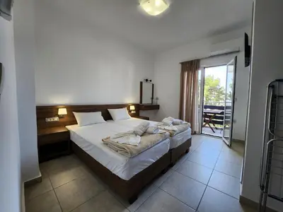 a bedroom with a large bed and a balcony at Tarra Rooms and Apartments in Agia Roumeli