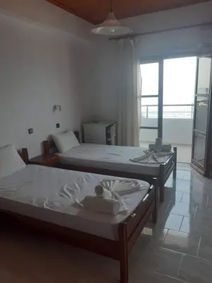 two beds in a room with a large window at Tarra Rooms and Apartments in Agia Roumeli