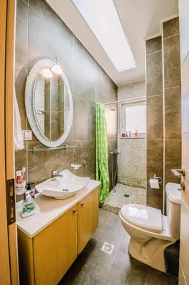 a bathroom with a sink and a toilet and a mirror at Mary's modern apartment in Kissamos