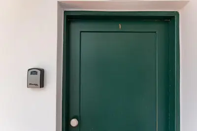 a green door with a clock on a wall at Central Kalyves Appartment - 5 min waking to the beach in Kalyves