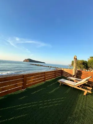 a deck with a table and a bench on the beach at Villa Tile in Agia Marina Nea Kydonias