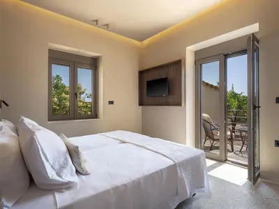 a bedroom with a bed and a tv and a balcony at Villa Portokalea in Maleme