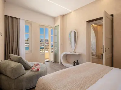 a bedroom with a bed and a chair and a mirror at Venetian Harbour Residence in Chania Town