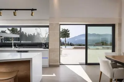 a kitchen with a large window and a table with chairs at Versante Rousso - Modern Living in Nature's Embrace by etouri in Káïna