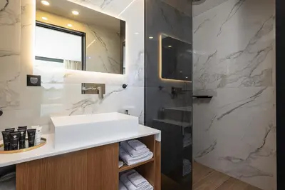 a bathroom with a white sink and a shower at Versante Rousso - Modern Living in Nature's Embrace by etouri in Káïna