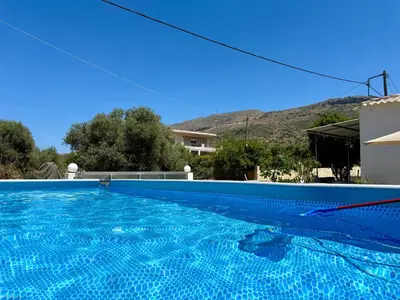 a blue swimming pool in front of a house at Cretan Blue Bungalow Chania in Chania Town