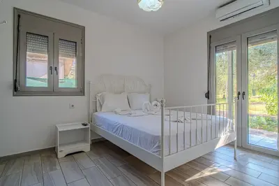 a white bedroom with a bed and a window at Cretan Blue Bungalow Chania in Chania Town