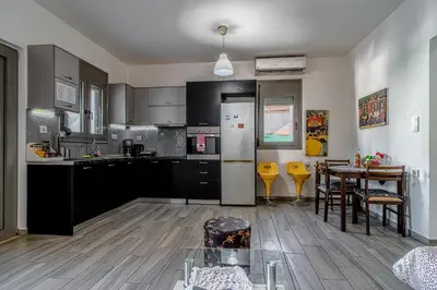 a kitchen with black cabinets and a table and a dining room at Cretan Blue Bungalow Chania in Chania Town