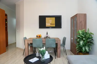 a living room with a table and chairs and a television at Happy House-Steps from Nea Chora Beach in Chania Town