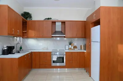 a kitchen with wooden cabinets and a white refrigerator at Happy House-Steps from Nea Chora Beach in Chania Town