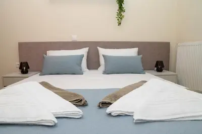 a large bed with white sheets and blue pillows at Happy House-Steps from Nea Chora Beach in Chania Town