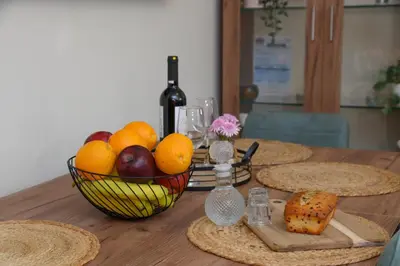a table with a basket of fruit and a bottle of wine at Happy House-Steps from Nea Chora Beach in Chania Town