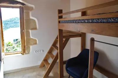 a room with a bunk bed and a chair and a window at The Village Hideaway - Traditional Stone House in Kissamos